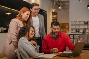 4 people collaborating and looking at a laptop